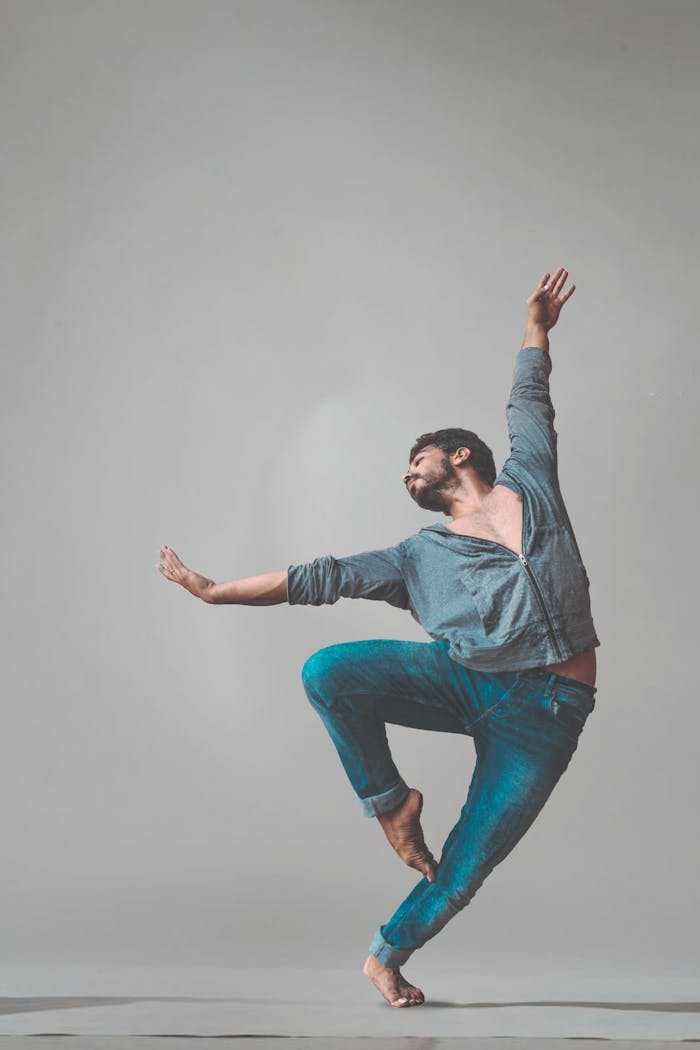 A male dancer strikes a dynamic pose in a studio setting, showcasing contemporary dance style.